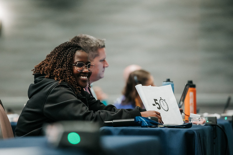 Person smiling at a table during an event.