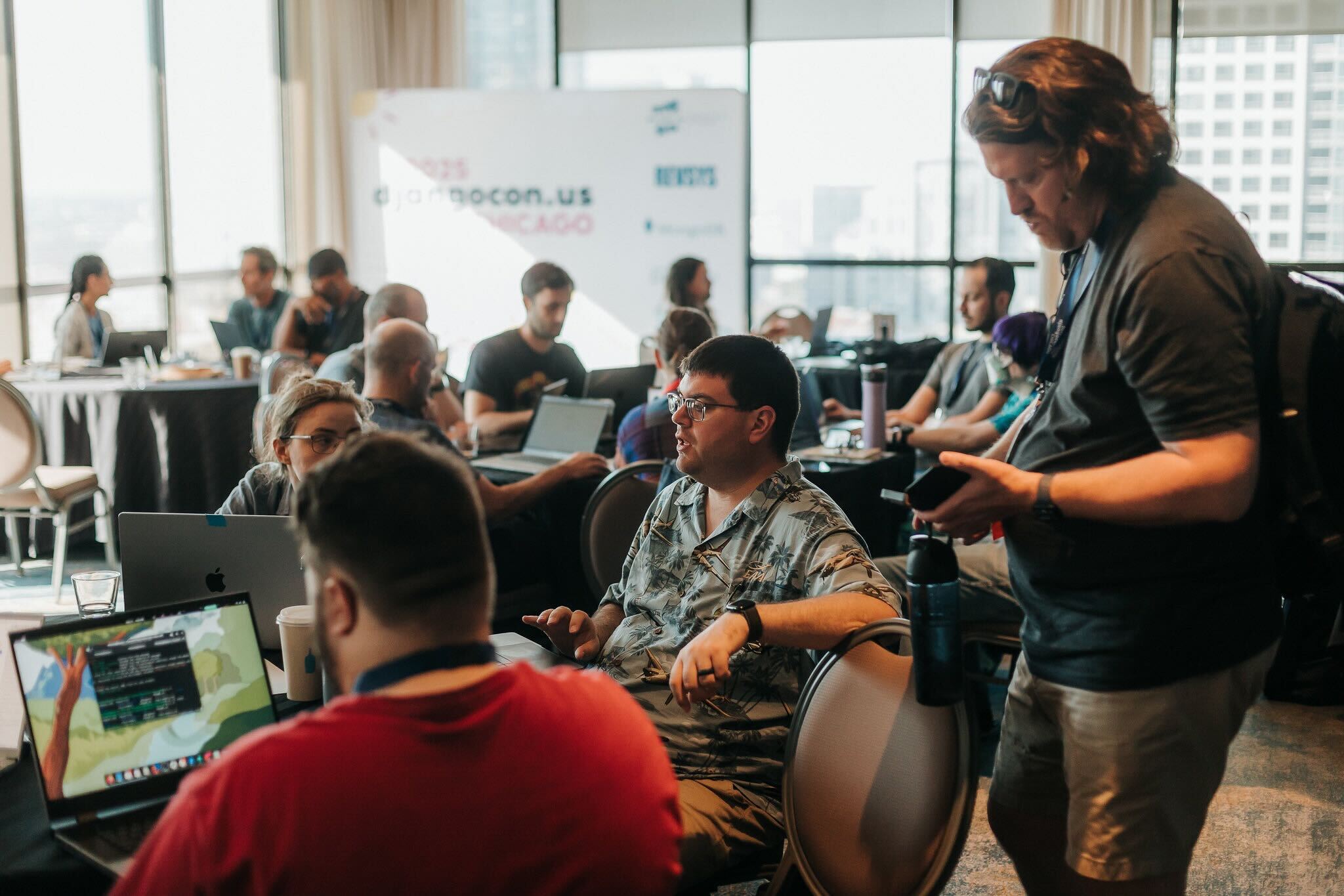 Two sprinters reviewing code together on a sticker-covered laptop.